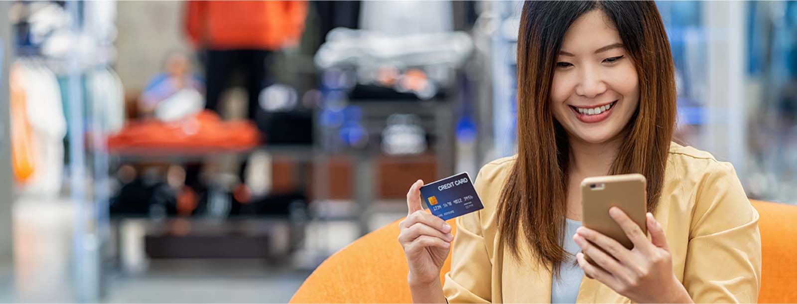 Lady looking at cell phone and holding a debit card